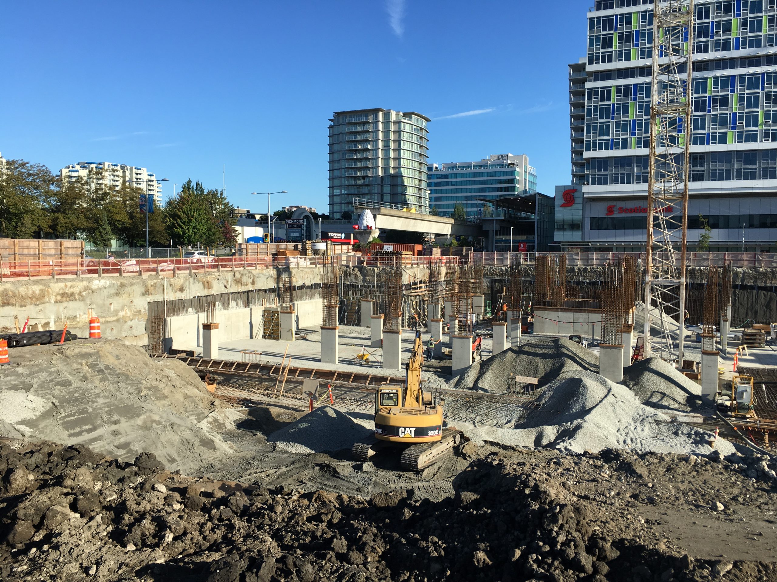 An excavator rests near a partially completed worksite for The Paramount development.